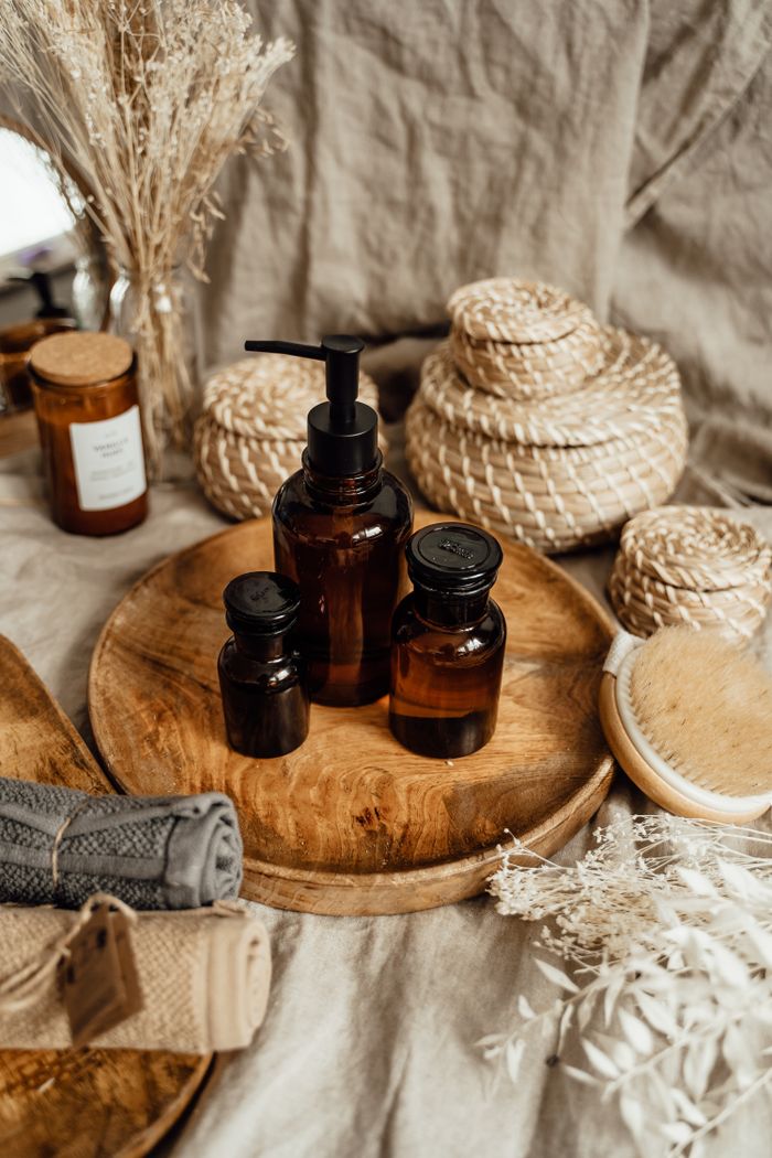 Brown glass bottles with skincare products on a wooden tray in a rustic, elegant arrangement.